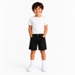 Smiling young boy wearing black denim shorts with a white t-shirt and white sneakers on a clean white background