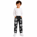 Young boy wearing black distressed denim jeans with all-over white daisy floral patch embroidery, white long-sleeve top, and white sneakers on a transparent background