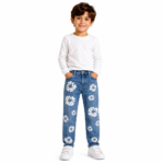 Front view of a smiling young boy wearing blue distressed denim jeans with all-over white daisy floral patch embroidery, white long-sleeve top, and white sneakers on a transparent background