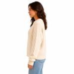 Side view of a female model wearing a cable-knit oversized women's pullover sweater showing the side silhouette, sleeve length, and knit texture