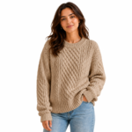 Female model wearing a tan/camel-coloured cable-knit oversized women's sweater with jeans in a product lifestyle shot showing colour and fit for knitwear brands